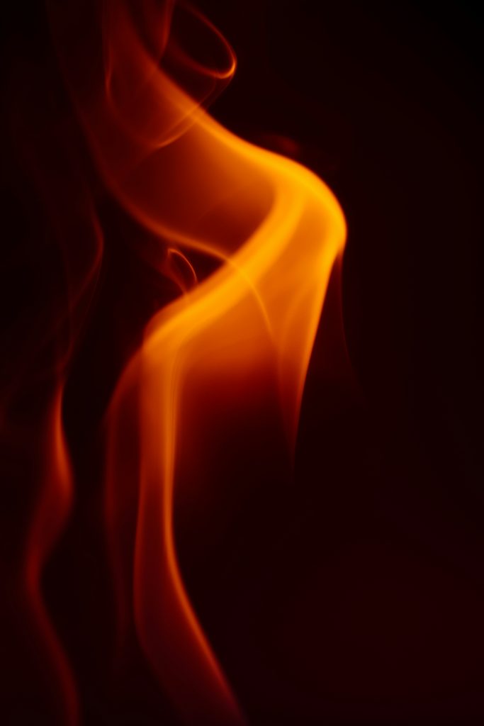 Schwarzer Hintergrund mit orangener Flamme im Vordergrund.